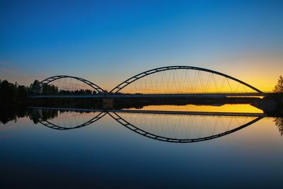 Arch bridge over river against sky during sunset