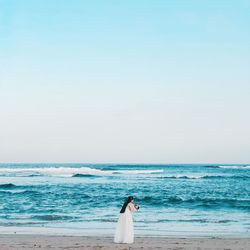 Woman looking at sea against clear sky