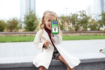 Girl showing vaccine certificate on smart phone