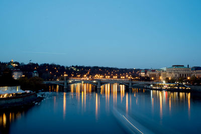 Illuminated bridge over river against sky at night