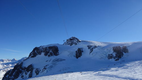Snow covered mountain against blue sky