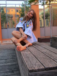 Young woman looking away while sitting on wood