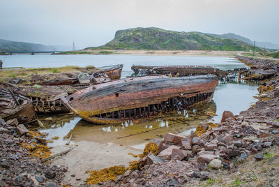 Abandoned boats on beach against sky