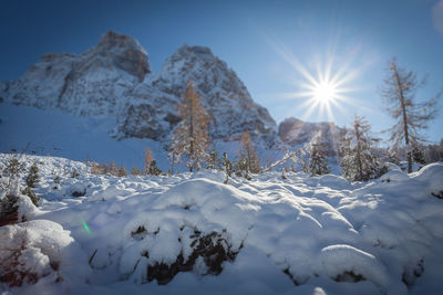 Scenic view of snow covered mountains against bright sun