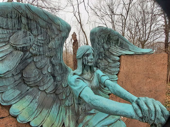 Low angle view of angel statue against trees