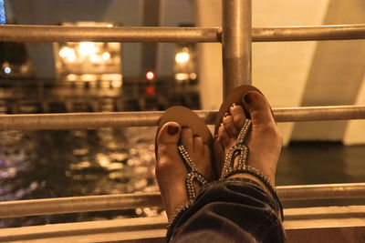 Low section of person wearing shoes on railing