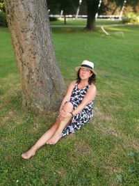 Portrait of young woman sitting on tree trunk