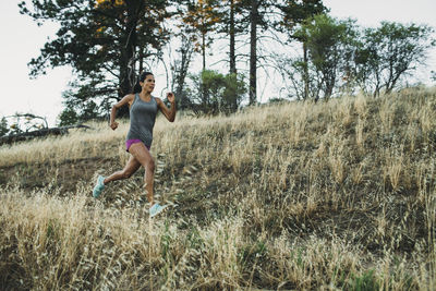 Side view of sportswoman running on grassy field