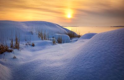 Scenic view of snow covered land during sunset