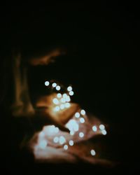 Defocused image of hand holding illuminated lights at night
