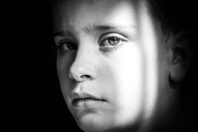 Close-up portrait of young woman against black background