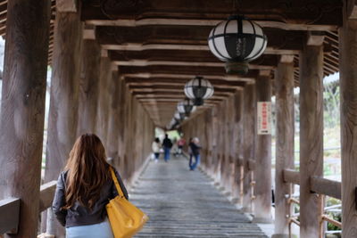 Rear view of woman walking on wooden footbridge