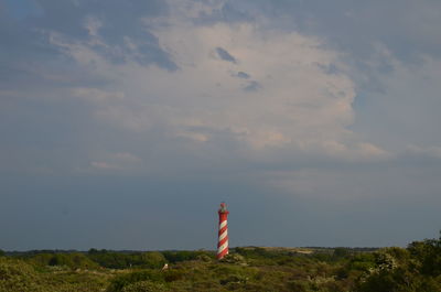 Lighthouse on field against sky