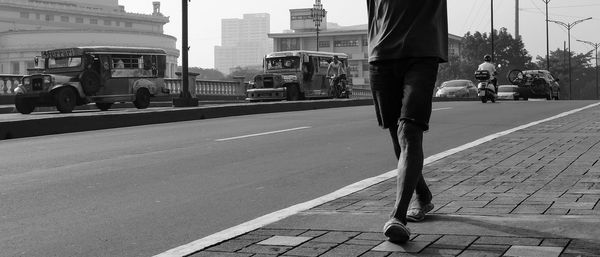 Low section of man walking on road