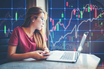 Young woman using mobile phone while sitting on table