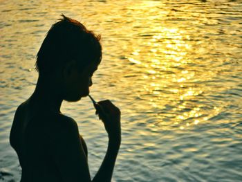 Silhouette woman in lake during sunset