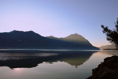 Scenic view of lake and mountains against clear blue sky