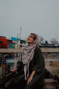 Portrait of young woman standing against sky