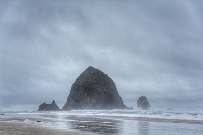 Rock formation on beach against sky