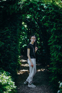 Portrait of a teenage girl in a botanical garden on a path with an arch.