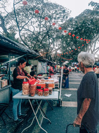 People standing by street market in city