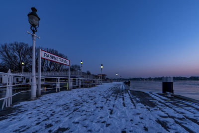 Illuminated street light against clear sky during winter at night