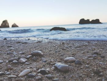 Close-up of pebbles on beach against clear sky