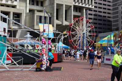 People in amusement park by buildings in city