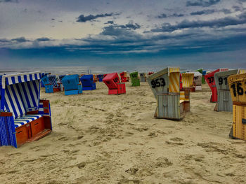 Hooded chairs on beach against sky