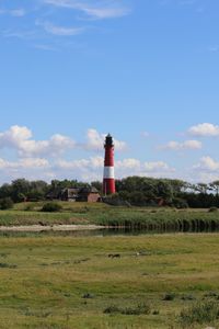 Lighthouse on field against sky