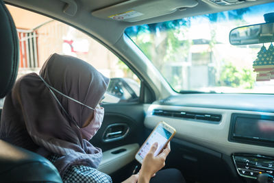 Midsection of woman using mobile phone in car