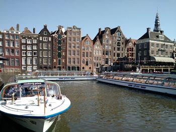 Sailboats in river by buildings in city against sky