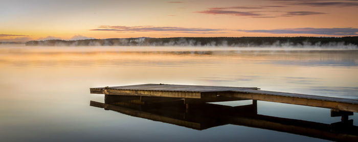 Pier over lake against sky during sunset