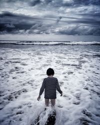 Rear view of girl standing on shore at beach