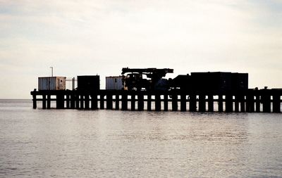 Silhouette built structure by sea against sky