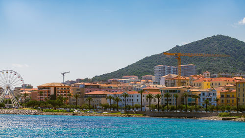 Buildings by river against clear sky