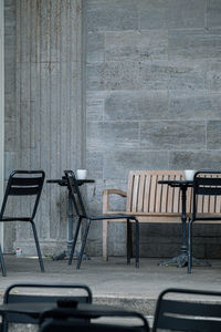 Empty chairs and table against wall