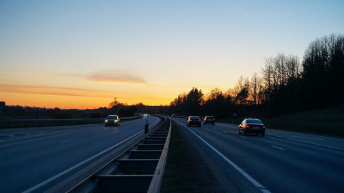 Cars on street against sky during sunset