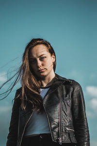 Low angle portrait of young woman against sky