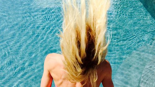 Rear view of woman with blond hair against swimming pool