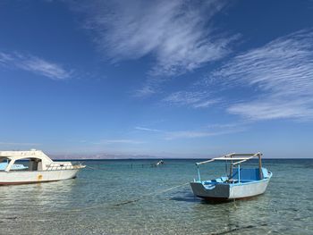 Boat moored in sea against blue sky