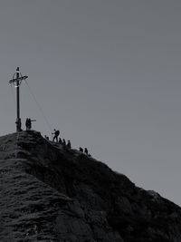 Low angle view of people on mountain against clear sky