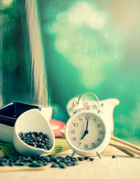 Close-up of alarm clock with coffee beans on table