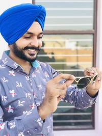 Close-up of young man wearing turban holding sunglasses