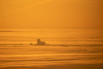 Scenic view above the clouds against orange sky