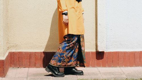 Low section of woman standing against wall