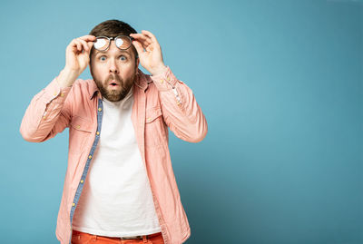 Portrait of man standing against blue background