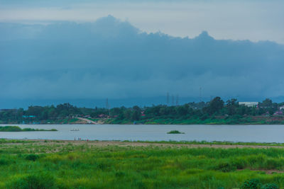 Scenic view of lake by field against sky