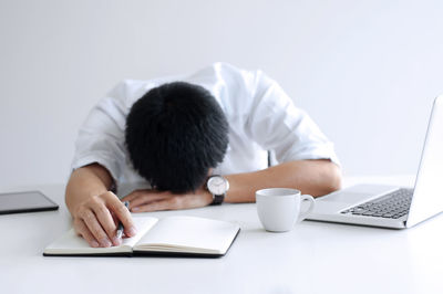 Rear view of man using laptop on table