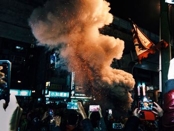 People photographing firework smoke during festival in city at night